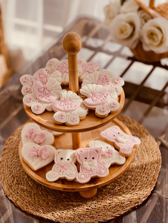 Adorable pink and white baby shower cookies arranged on a tiered wooden stand.