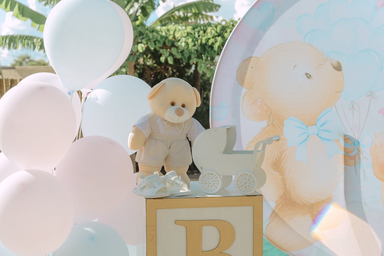 Adorable baby shower decoration featuring balloons, a stuffed teddy bear, and stroller cutout, creating a joyful atmosphere.
